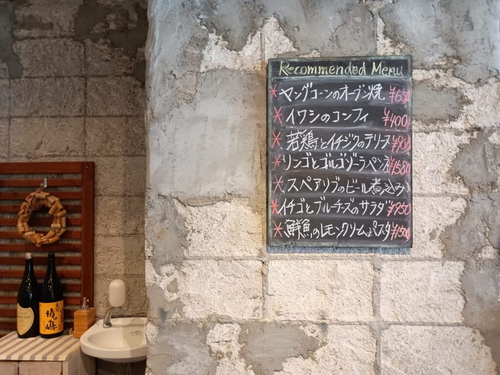 おすすめメニューの黒板:
石壁に掛けられた黒板の「Recommended Menu」。ヤングコーンのオーブン焼、イワシのコンフィ、若鶏とイチジクのテリーヌ、リンゴとゴルゴンゾーラのペンネなど、おすすめの一品料理が手書きで並ぶ