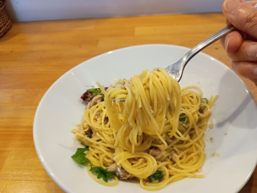 パスタ(箸上げ):
フォークに巻き上げたサバのコンフィと大葉のペペロンチーノのアップ。細めのスパゲッティがつややかに光っている